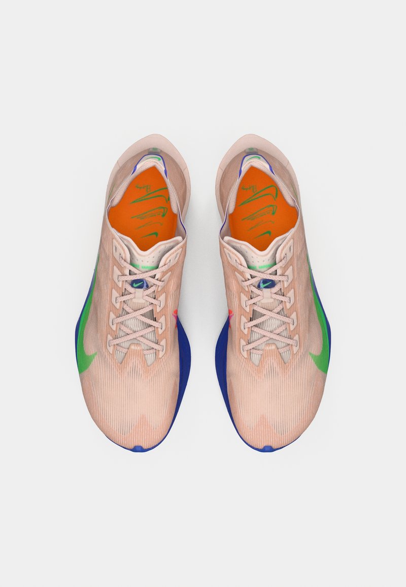 Par af lyserøde træningssko med grøn swoosh, blå mellemsåler og orange indersåler med grønne logoer, set fra oven.