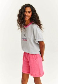 Šedé tričko s krátkým rukávem a růžovým výstřihem, doplněné světle růžovými lněnými šortkami s ohrnutými manžetami a elastickým pasem.