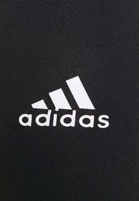 Tissu athlétique noir avec un logo Adidas blanc, accompagné du logo des trois bandes et du nom de la marque en police grasse et lisible.