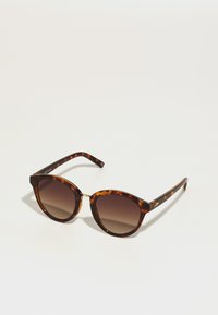 Ochelari de soare cu rame în stil țestoasă, lentile maro cu gradient. Formă de ochi de pisică, accent auriu lângă balama, brațe negre elegante cu detalii decorative.