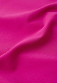 Tissu rose vif avec une texture lisse et des plis doux créant des ombres et des reflets délicats.
