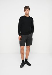 Sort ribbet sweater, charcoal cargo shorts, sorte loafers, ankel sokker; enkelt design, afslappet fit, glat tekstur, ingen synlige mønstre.