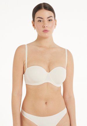 Sostenedor acolchado beige con tirantes finos ajustables, varilla de soporte, tela suave y un diseño contorneado para dar forma.