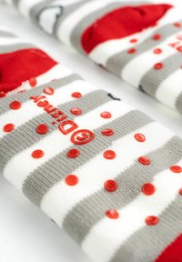 Calzini a righe in grigio, bianco e rosso. Presentano pallini di gomma rossa per grip e il logo "Disney" in rosso su sfondo grigio. Texture morbida.