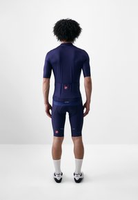 Marineblaues Fahrradtrikot und -shorts aus elastischem Material, mit kurzen Ärmeln und Rückentaschen; ausgestattet mit rotem Branding und reflektierenden Akzenten.