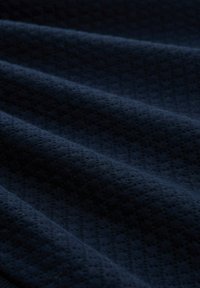 Tela azul marino con una superficie texturizada, que presenta un sutil patrón de diamantes y suaves fibras ligeramente elevadas, creando una apariencia lisa y rica.
