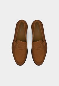 Paire de mocassins marron en daim à enfiler, avec bouts ronds et détails cousus, vue de dessus sur fond blanc.