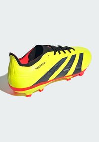 Scarpa da calcio gialla brillante con strisce nere, lacci neri e dettagli rossi. Presenta un design elegante e una superficie testurizzata per una migliore presa.