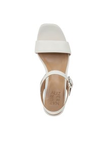 Sandal bianca con punta aperta, dotata di una larga fascia frontale, una fibbia sottile alla caviglia e un morbido plantare color marrone.