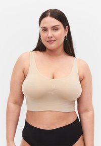 Beige crop top med breda axelband, slät textur, subtil samling i mitten, matchad med svarta hög midja underkläder.