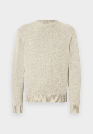 Pull en tricot beige clair avec col rond, manches longues et poignets côtelés. La texture est douce avec un motif subtil et fin sur toute la surface.