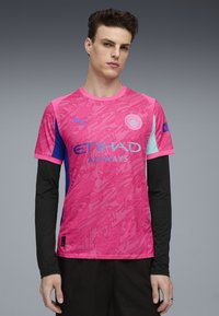 Rosa sportströja med en strukturerad mönster, svarta långa ärmar och blå detaljer. Visar "ETIHAD AIRWAYS" och en logotyp.