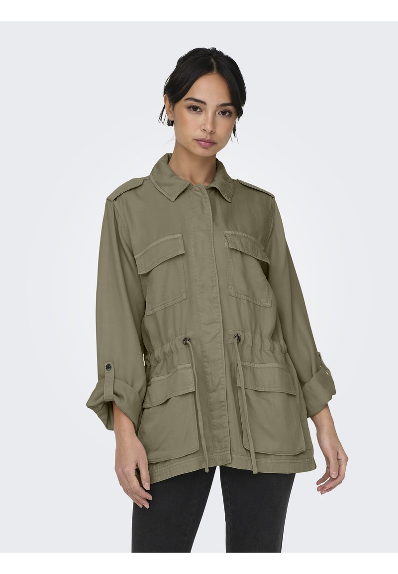 Veste utilitaire vert olive en tissu léger, dotée d'une taille à cordon de serrage, de deux poches poitrine et d'un devant boutonné avec des manches retroussées.