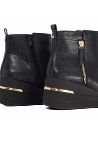 Zwarte nep leren enkellaarsjes met textuurelementen, gouden ritsdetail en een wigzool met een metallic streep. Glad afgewerkt.