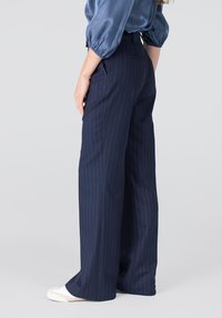 Navyblauwe wijde broek met een streeppatroon, hoge taille en zakken. Glad materiaal met een subtiele glans.