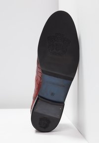 Chaussure en cuir rouge avec un design texturé et tissé. Semelle en caoutchouc noir avec un logo et la taille 37. Fini lisse et forme élégante.