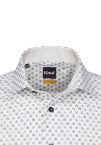 Camicia bianca con motivo floreale blu, taglio moderno, con colletto interno in tinta unita e bottoni neri. Etichetta della taglia visibile.