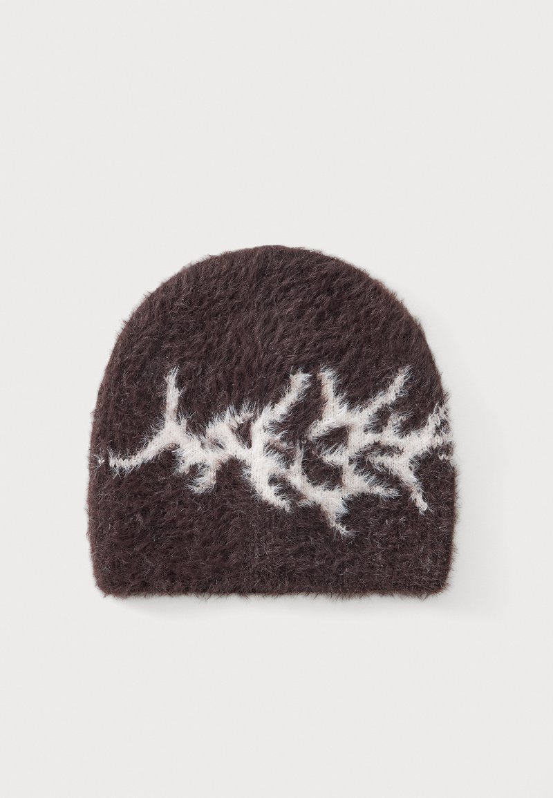 Bonnet marron foncé duveteux avec un motif abstrait en zigzag blanc au centre sur un fond clair.