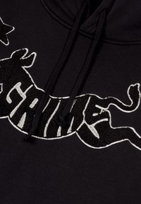 Black hoodie featuring a large, textured white embroidered graphic of a running cow and the word "GRIME" in stylized lettering.
