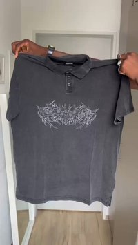 Černé polo tričko vyrobené z bavlny, s grafickým designem s hmyzem a textem v šedé barvě. Krátké rukávy a zapínání na tři knoflíky.