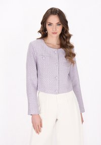 Giacca accorciata lavanda realizzata in tessuto texturizzato, con scollatura rotonda, chiusura con bottoni e due tasche frontali. Abbinata a pantaloni bianchi.