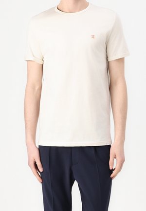 Beżowa bawełniana koszulka z okrągłym dekoltem i krótkimi rękawami. Posiada małe pomarańczowe logo "II" na lewej piersi.