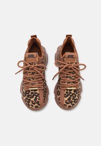 Paire de baskets marron avec imprimé léopard et paillettes, semelles épaisses, et lacets marron noués en nœuds sur fond blanc.