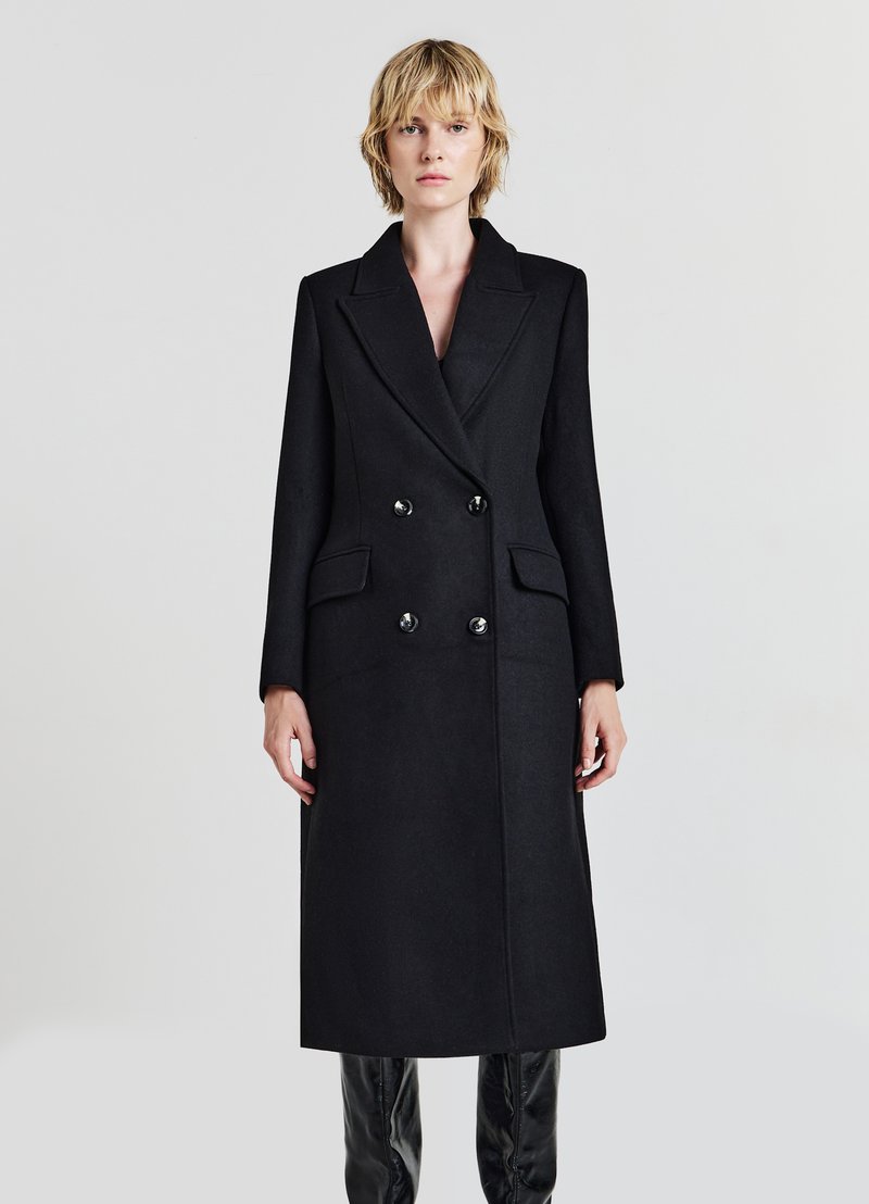 Cappotto in misto lana nero con design doppiopetto, ampi rever, due tasche frontali e bottoni neri lucidi. Vestibilità su misura e maniche lunghe.