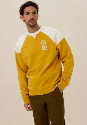 Gelbes Sweatshirt mit weißen Raglanärmeln, ausgestattet mit einem grafischen Logo und einem runden Ausschnitt. Weicher Stoff, lässige Passform.