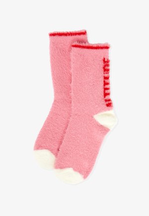 Calzini rosa morbidi con una texture in spugna, bordatura rossa nella parte superiore e dettagli bianchi su punta e tacco.