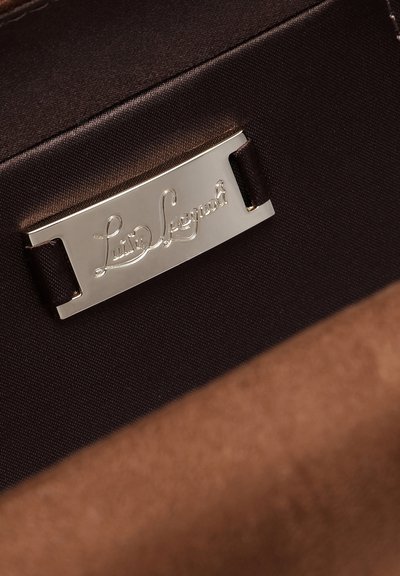 Metalskilt med indgraveret "Luca Legnoli", fastgjort til mørkebrun stof indeni en blødtekstureret brun taske.