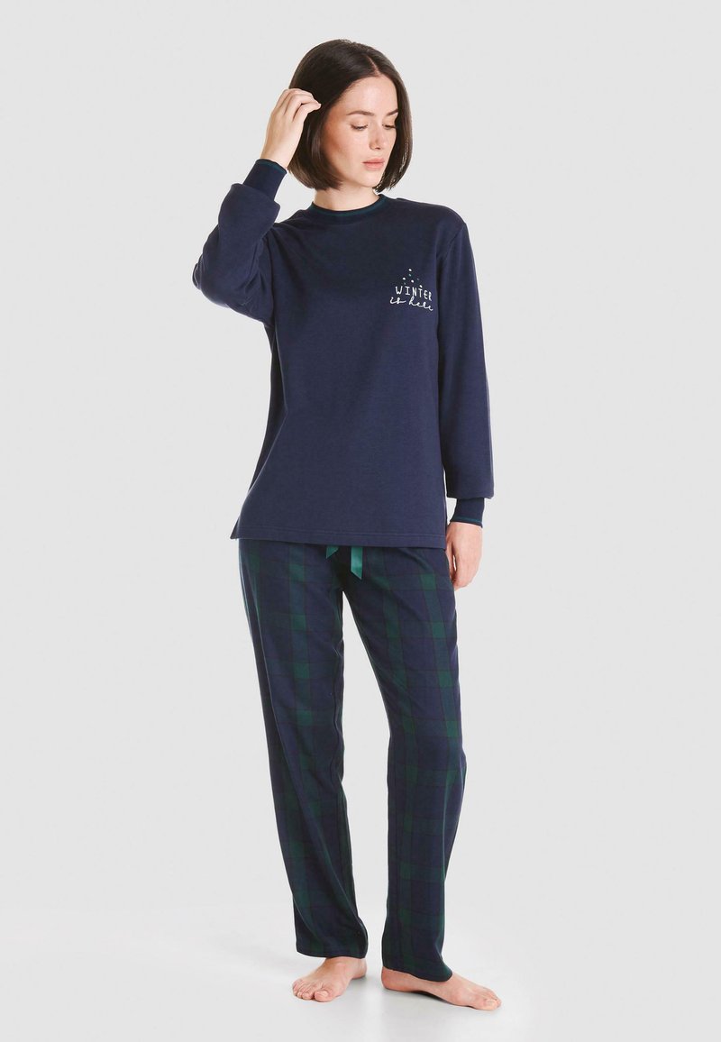 Camiseta de pijama de manga larga en navy con el estampado "El invierno es fresco", combinada con pantalones de cuadros en verde y navy, con cintura ajustable.
