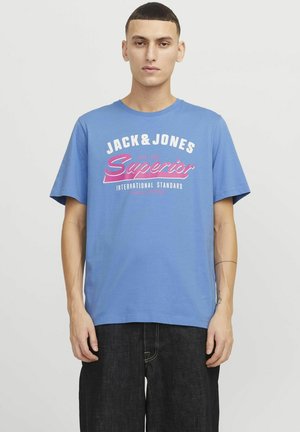 Plava pamučna majica s kratkim rukavima, s bijelim i ružičastim natpisima "JACK&JONES Superior" i "INTERNATIONAL STANDARD" na prednjoj strani.