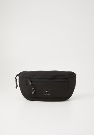 Svart tygpåse med rund form, dragkedjeslutning, snörningsdetaljer och en framsidan logotypplåster på en strukturerad yta. Idealisk för små föremål.