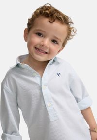 Camisa de botones a rayas azul claro hecha de algodón. Presenta un cuello con solapa, mangas arremangadas y un pequeño logo bordado en el pecho.