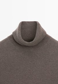 Brązowy sweter typu golf z dzianiny o prążkowanej strukturze i złożonym kołnierzem. Charakteryzuje się jednolitym kolorem bez widocznych wzorów ani akcentów.