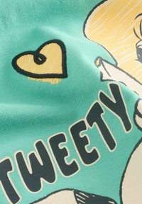 Grüner Stoff mit einer Cartoonfigur und dem Wort "TWEETY" in fetten, dunklen Buchstaben. Mit einem gelben Herzdesign und glatter Textur.