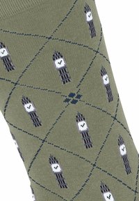 Grüne Socken mit einem sich wiederholenden Muster von Big Ben in Schwarz und Weiß, angeordnet in einem Rautennetz mit navyblauen Akzenten. Weiche Stricktextur.