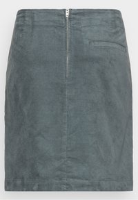 Jupe en denim gris, longueur genou, avec une fermeture éclair visible à l'arrière et une poche latérale. Tissu texturé avec une finition à motif subtil.
