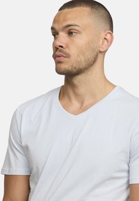 T-shirt bleu clair à manches courtes, design en V, fabriqué en tissu doux, avec une texture lisse et des détails de couture réguliers.