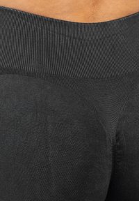 Czarne legginsy z ribbowanym pasem, gładką teksturą i dopasowanym krojem. Prezentują się bezszwowo w okolicy bioder.