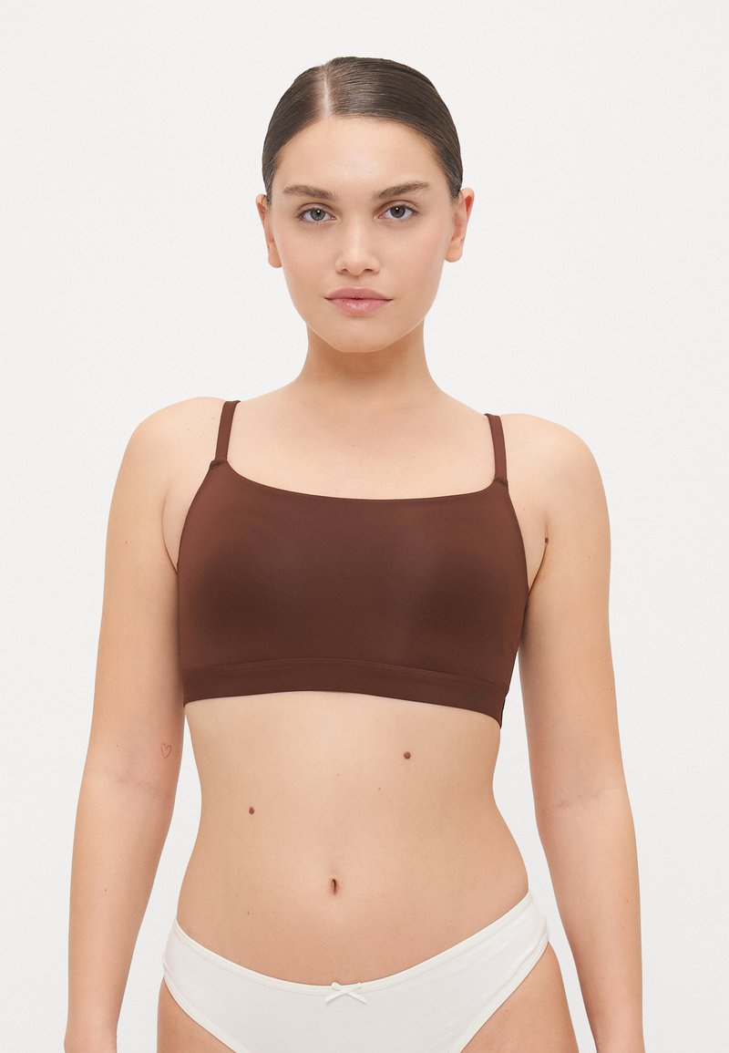 Brown seamless bralette with thin straps, featuring a square neckline and soft texture, paired with a white bikini bottom.