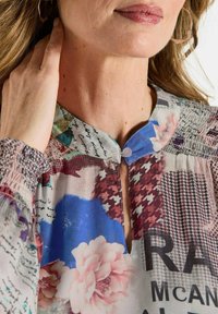 Multikleurige blouse met een bloemen- en tekstprint, voorzien van een keyhole-halslijn, geplooide manchetten en een zachte, lichte stof.