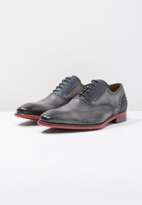 Scarpe eleganti in pelle grigia con dettagli brogue, accenti testurizzati blu e suole rosse. Presentano una finitura liscia e un design classico con lacci.
