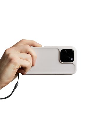 Main tenant un smartphone avec une coque de protection pâle et des objectifs de caméra visibles, attaché à une sangle noire pour poignet.