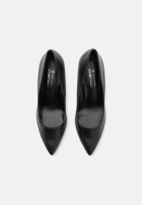 Talons hauts en cuir vegan noir avec un design à bout pointu, texture lisse et empeigne en forme d'amande mettant en avant un style minimaliste.