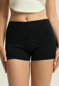 Czarne rybaczki z dopasowanym krojem. Gładka faktura i czyste linie, z bezszwowym pasem dla wygody.