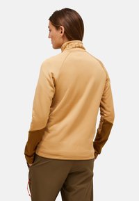 Pullover in pile beige con colletto alto, maniche marroni a contrasto e una texture liscia. Logo presente sul colletto.