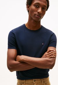 Marineblå kortærmet T-shirt med rund hals i blødt stof, med en lille logo-accent på brystet. Glat tekstur og tætsiddende design.