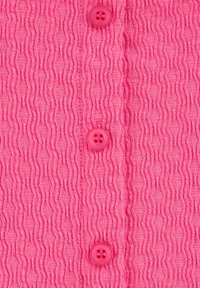 Rozā teksturēta auduma ar viļņotu rakstu un četriem saskaņotiem pogām. Pogas ir apaļas un katrai ir četri caurumi.